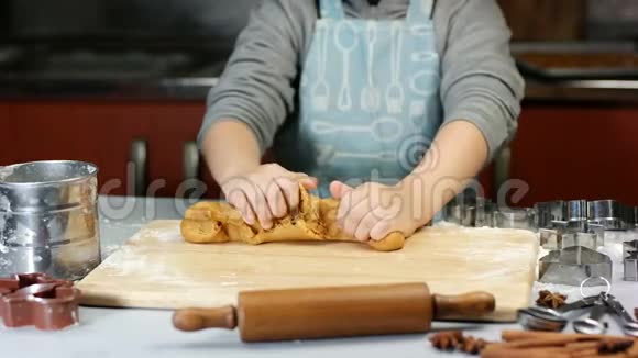 五岁的男孩为圣诞姜饼饼干揉面团桌子上的金属刀具面粉和卷笔视频的预览图