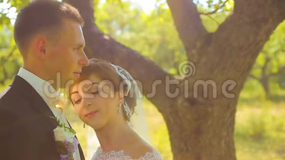 快乐的新娘和新郎美丽的女孩拥抱和亲吻在森林里视频的预览图