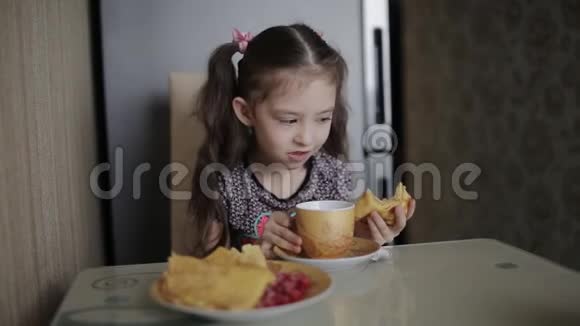 厨房里的小女孩吃着煎饼和茶的早餐视频的预览图
