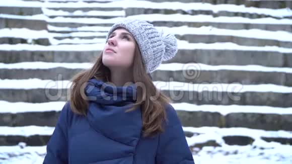 穿着冬装帽子和围巾的美丽年轻微笑的白种人女子的特写肖像布鲁纳女孩雪木视频的预览图