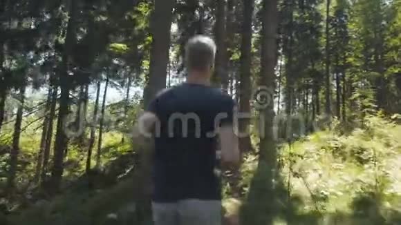 阳光明媚的白天英俊的白种人在森林里奔跑视频的预览图