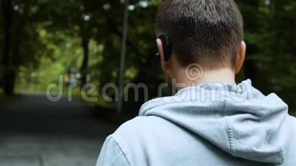 在秋天公园跑步者用蓝牙耳机通过电话交谈视频的预览图