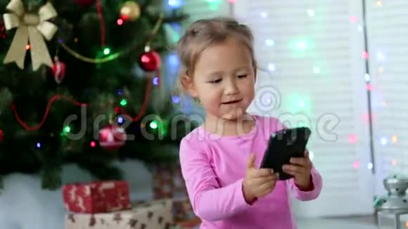 小可爱的女孩在背景上用圣诞树自拍视频的预览图
