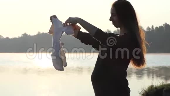 一位孕妇在日落时分为她的孩子穿上浪漫的套装视频的预览图