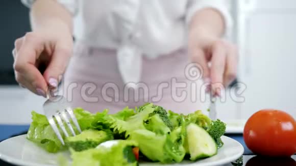 女人在厨房里混合新鲜的有机绿色沙拉生菜和西兰花和黄瓜视频的预览图