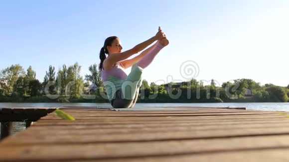 穿运动服的女孩在小木码头做瑜伽视频的预览图