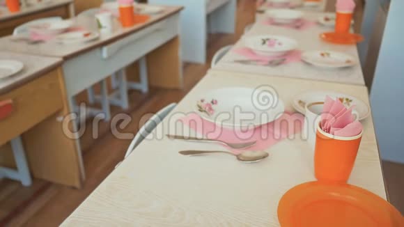 幼儿园里有盘子杯子叉子和勺子的餐桌小女孩准备午休视频的预览图