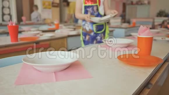 幼儿园里有盘子杯子叉子和勺子的餐桌小女孩准备午休视频的预览图