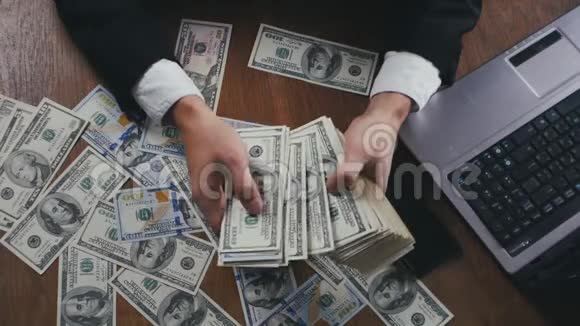 一个商人坐在办公室的桌子上数着钱紧紧地握住他的手薪酬或利润的概念视频的预览图