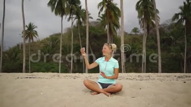 坐在沙滩上视频聊天的年轻女子视频的预览图