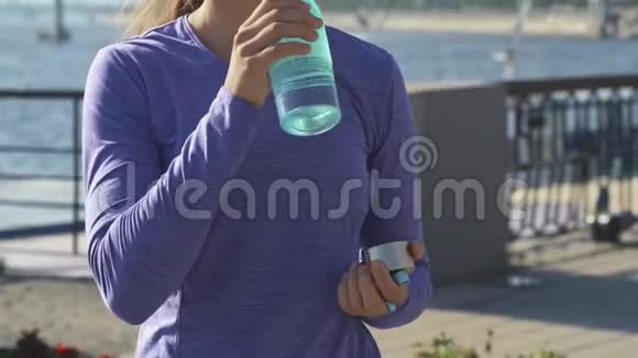 女人在美丽的背景上喝水的动作镜头视频的预览图