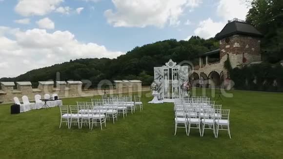 白色结婚椅婚礼设在花园里婚礼前在草坪上放一排排白色木制空椅视频的预览图