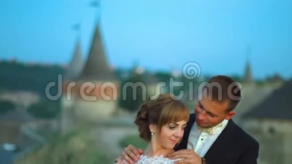 可爱的新婚夫妇在城堡日落4k附近亲吻拥抱视频的预览图