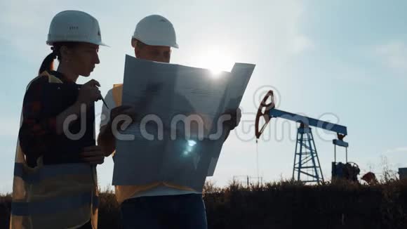 一个工程师小组正在讨论一个油田的维修问题在炼油厂工作的工程队两个工人视频的预览图