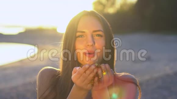 美丽的女人在海滩上缓慢地吹着纸屑白种人快乐的少女吹金闪闪视频的预览图