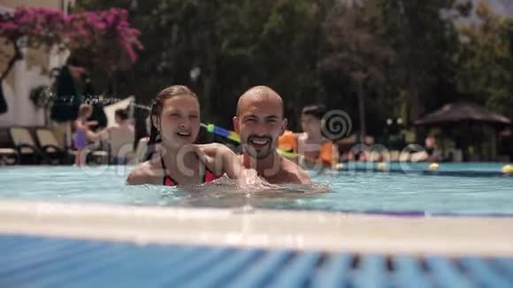 年轻的爸爸和一个女儿在游泳池里玩耍和嬉戏视频的预览图