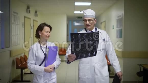 穿着实验室外套的男医生和女医生穿过病房的走廊讨论基因图视频的预览图