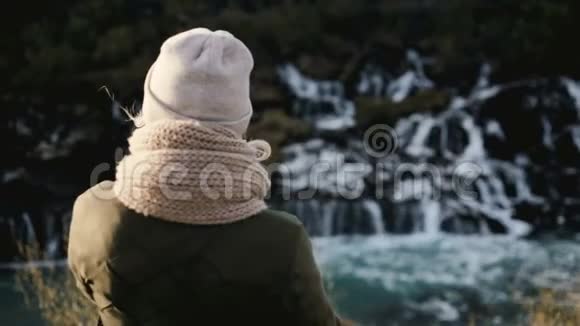 后景年轻美丽的女人站在冰岛的Barnafoss瀑布附近欣赏风景优美的风景视频的预览图