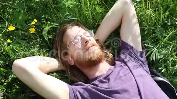 年轻的红发男子躺在草地上放松视频的预览图