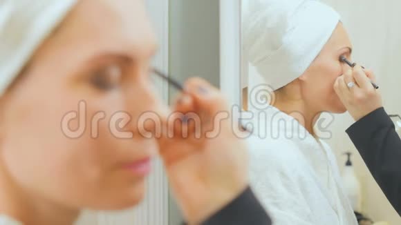 美容师在年轻女子的眼皮上涂上眼影视频的预览图