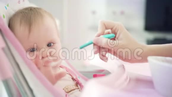 宝宝用勺子吃饭可爱的孩子尝粥幼儿在婴儿椅上吃饭视频的预览图