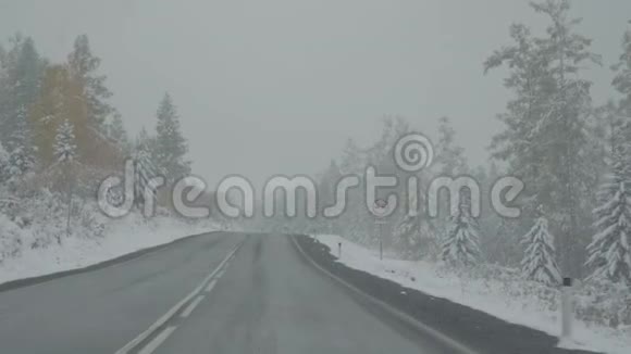 驾驶汽车在冬季山路上下雪视频的预览图