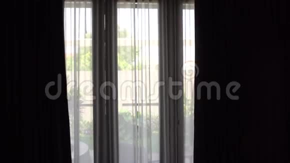 穿着浴袍的年轻女子把窗帘拉上靠近家中的窗户视频的预览图