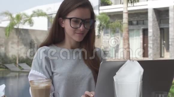 美丽的年轻女子在笔记本电脑上工作在豪华别墅的游泳池附近微笑女性在电脑上工作热巧克力视频的预览图