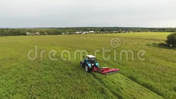 蓝色大拖拉机用长方形的红色割草机慢慢地割草视频的预览图