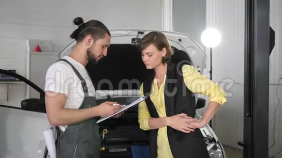 一位年轻的机械师站在汽车旁边视频的预览图