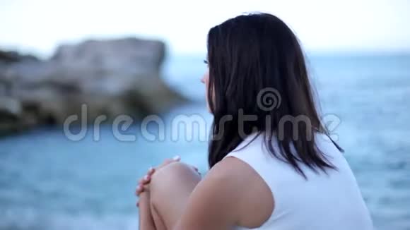 美丽的年轻女子鲜红的嘴唇坐在海滨视频的预览图