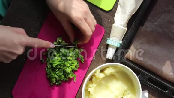 女人洋葱羽毛在切割板上旁边的其他食材做菜饭土豆泥烤片视频的预览图