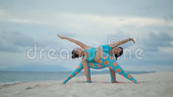 两个亚洲女人在海边做瑜伽姿势视频的预览图