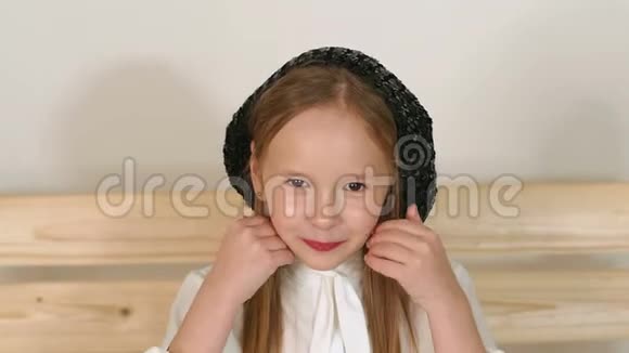 一个戴着黑色老式帽子的小女孩在工作室里摆着白色背景视频的预览图