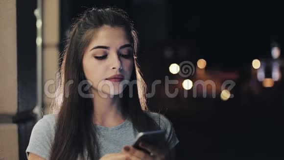 年轻迷人的女人在夜城的街道上使用手机女性使用智能手机进行商务交流视频的预览图