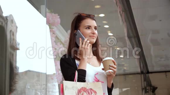 街头购物的魅力女士喝咖啡打电话视频的预览图