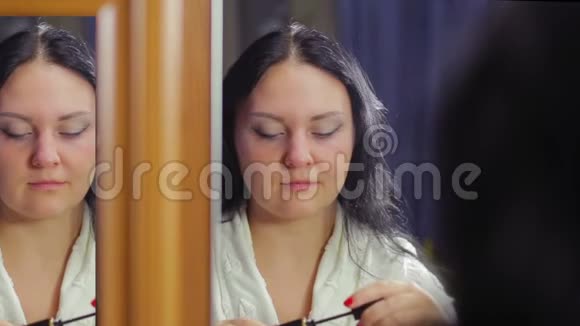 镜子前的年轻女子把睫毛膏涂在睫毛上视频的预览图