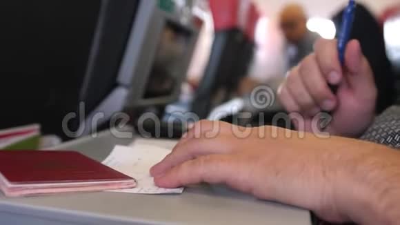 持护照的男性乘客在飞机上填写迁徙或抵达卡视频的预览图