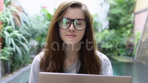 戴眼镜的女人用笔记本电脑写文章女商人在度假期间在电脑上工作视频的预览图