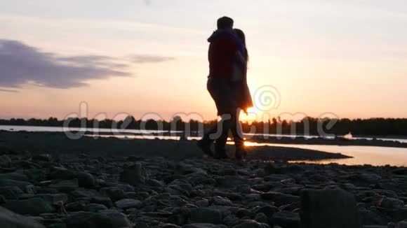 恋爱中的情侣在河边日落时拥抱和旋转高清1920x1080慢动作视频的预览图