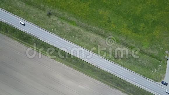从无人驾驶飞机在道路上的空中俯瞰移动的汽车在田野中行驶视频的预览图