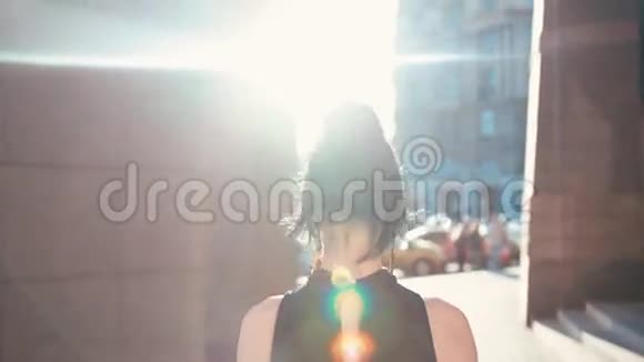 在明亮的阳光下美丽的黑发女人走在拥挤的城市街道上转向相机和视频的预览图