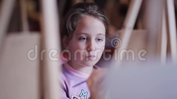 一个漂亮的小女孩正在画布上画一幅画早期开发工作室艺术工作室视频的预览图