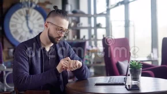 男人手上的智能手表希普斯特坐在咖啡馆里用他的智能手表他可以查看信息激活信息视频的预览图