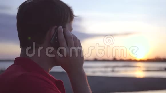 男人在电话里说话背景是夕阳下的河高清1920x1080慢动作视频的预览图