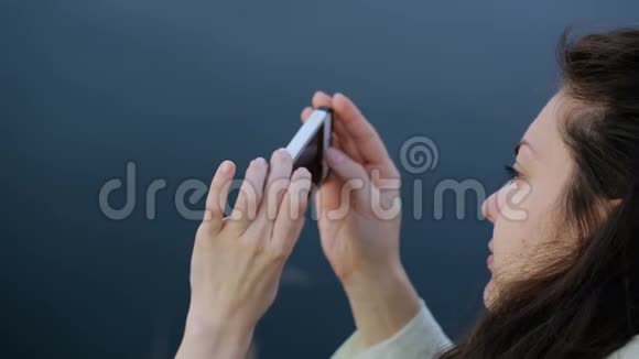年轻的黑发女人用手机拍照视频的预览图