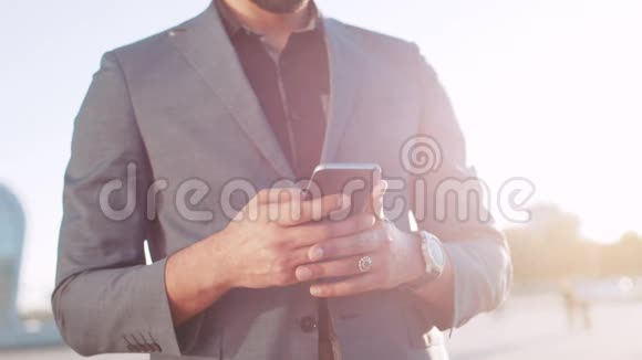 穿西装的热辣商人戴着墨镜用手机用手机检查他的智能手表的时间然后进入视频的预览图