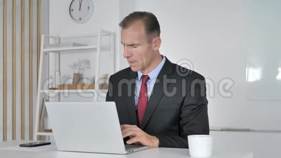 中年商人在手提电脑工作时打哈欠视频的预览图