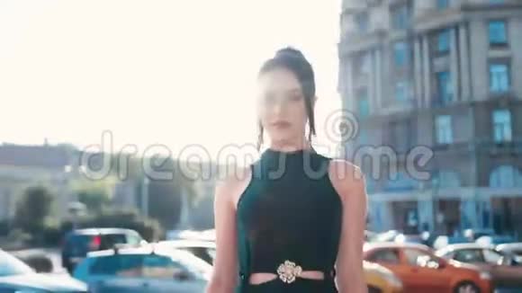 自信迷人的黑发女人穿着黑色连衣裙走在城市的街道上诱人地看着就在城市的右边视频的预览图