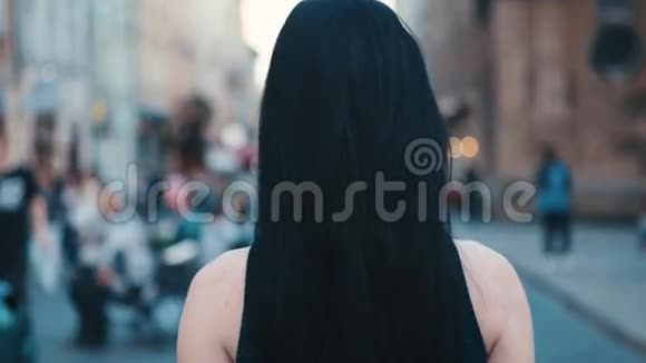 在拥挤的街道上美丽的黑发女人的后景她转向相机给人一种诱人的外观视频的预览图